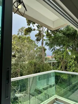 a glass balcony with a view of trees at AYAAN SOCCER HOME at Quintet Apartment with Free Parking in Tanah Rata