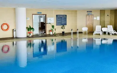 a large swimming pool in a hotel with chairs and tables at 118 Island Plaza Seaview Family Suite 5Pax 1Carpark in George Town