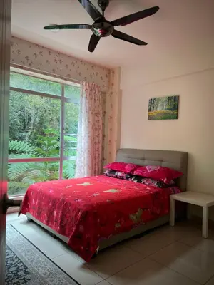 a bedroom with a bed with a red comforter and a window at Cameronian Lodge by AziziCameron in Tanah Rata