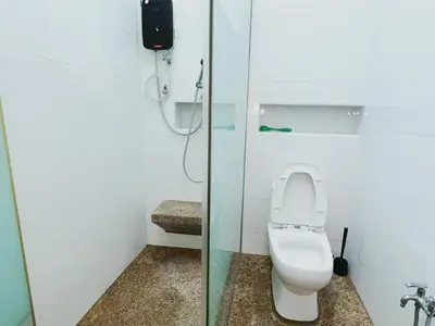 a bathroom with a toilet and a glass shower stall at Cozy Private Room for Relaxing Stays in Nibung Tebal