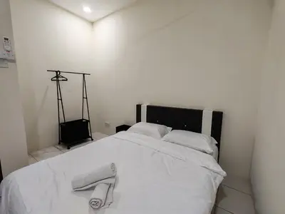 a white bed with two towels on top of it at EcoPutra Stay in Ipoh