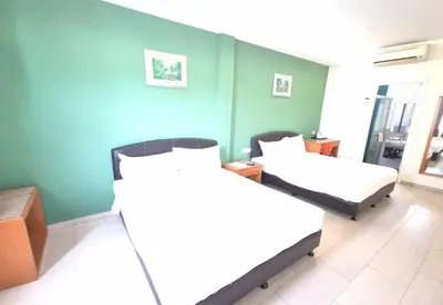 two beds in a room with green walls at Hotel Grand Court Inn in Sungai Besar