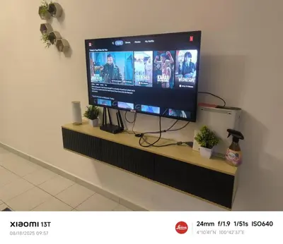 a flat screen tv on a wall with potted plants at damai homestay - feel like a home in Sitiawan