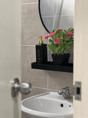 a bathroom with a sink and a mirror and flowers at Nahyra Homestay, Múslīm Only, WIFI, Netflix, 4 Bilik in Sungai Petani