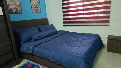 a bed with a blue comforter in a bedroom at Azura Homestay Seri Iskandar in Seri Iskandar