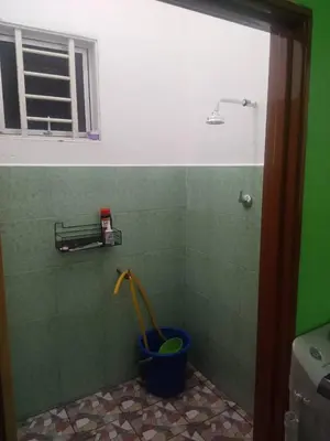 a shower in a bathroom with a bucket with a hose at Homestay Saadiah in Sungai Besar