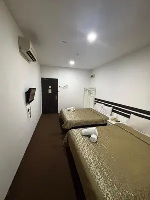 a room with two beds and a tv on the wall at Swing & Pillows - Grand Inn George Town Penang in George Town