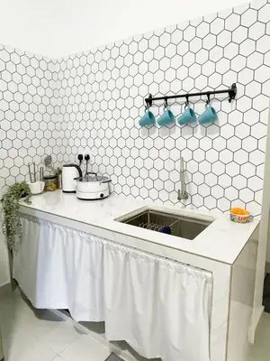a kitchen with a sink and a white tiled wall at Rumah Huda in Bukit Mertajam