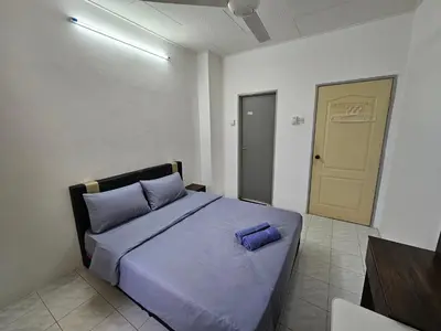 a bedroom with a bed with purple sheets and a door at Pera House Hostel in Ipoh