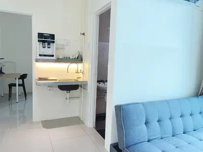 a living room with a blue couch and a kitchen at Cozy 2-Bedroom Balcony Suite with Living Room in Nibung Tebal