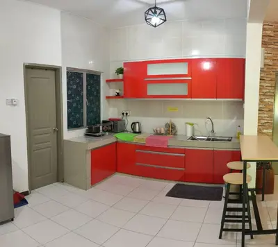 a kitchen with red cabinets and a sink and a table at StayIndah Homestay Cameron Highlands in Tanah Rata