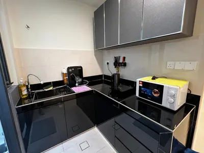 a kitchen with a black counter top with a microwave at AP Homestay in Sekincan