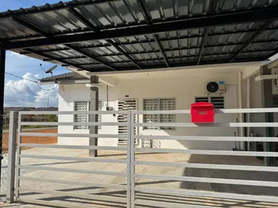 a white house with a fence and a red trash can at Harees Homestay in Kuala Lipis