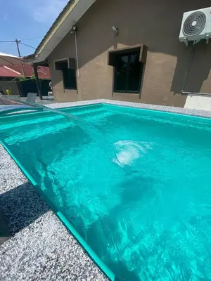 a swimming pool with blue water in front of a house at Asu Homestay w Private Pool - Batu Gajah,Perak in Batu Gajah