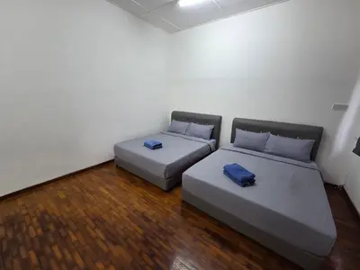 two beds in a small room with wood floors at Ipoh Stadium Hostel in Ipoh