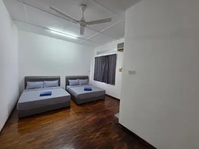 a room with two beds and a ceiling fan at Ipoh Stadium Hostel in Ipoh