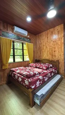 a bedroom with a bed with red sheets and a window at D'Kebun Lenggong Perak Chalet in Gua Sai