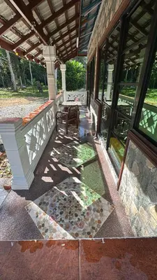 a porch of a house with a table and windows at D'Kebun Lenggong Perak Chalet in Gua Sai