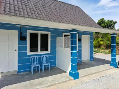 a blue and white cottage with two chairs at Teratak Sumayyah 2 - For Islam only - Pondok Lenggong in Kampong Banggol Belimbing