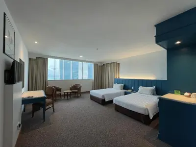 a hotel room with two beds and a table at Hotel Continental Penang in George Town
