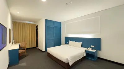 a bedroom with a blue and white bed and a chair at Hotel Continental Penang in George Town