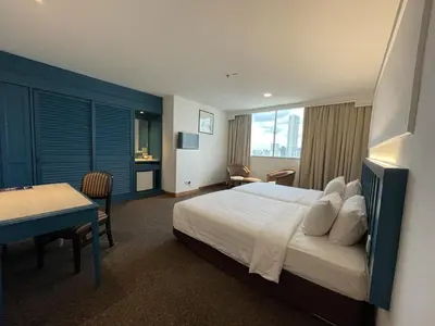 a hotel room with a bed and a table and a desk at Hotel Continental Penang in George Town