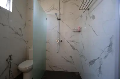 a bathroom with a toilet and a shower with marble walls at Coconut Bay beach Villa seaview karaoke 20pax in Tanjung Bungah