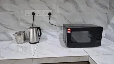 a microwave sitting on a counter next to a coffee pot at Hatasan Homestay Guess House