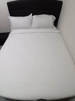 a white bed with two pillows on top of it at Sun Hotel Penang in George Town