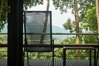 a black chair sitting on a porch with a view at Amazing Mountain View Lodge with Pool in Kuala Kubu Baharu