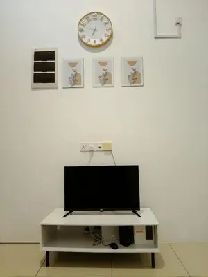 a flat screen tv on a white wall with a clock at D' Ara SZ Homestay in Kubang Semang