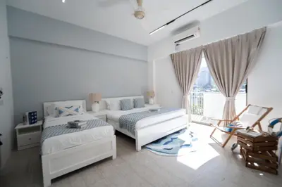 a white bedroom with two beds and a window at By The Sea Haven 2BR 6pax in Batu Ferringhi