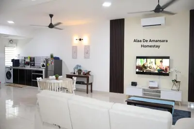 a living room with white furniture and a tv on a wall at Alaa De Amansara Homestay in Kepala Batas