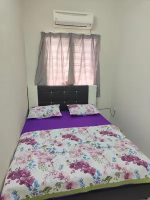 a bedroom with a bed with a floral bedspread at Margosa Homestay in Ipoh