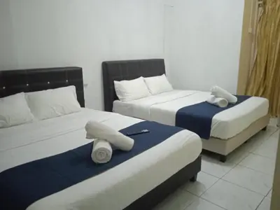 two beds in a hotel room with towels on them at Rest N Go CH in Tanah Rata