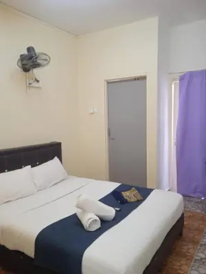 a bedroom with a large bed with a fan on it at Rest N Go CH in Tanah Rata