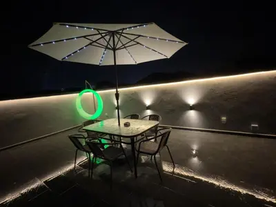 a table with an umbrella on a balcony at night at LYL 108 Private Pool Villa in Ipoh