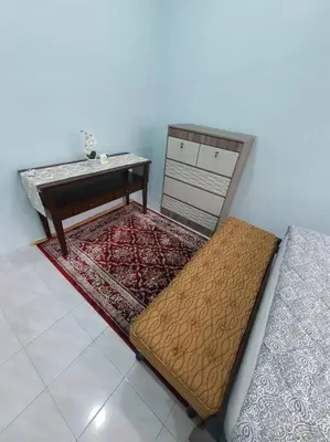 a room with a bed and a table and rug at Lumut Homestay for Muslims in Lumut