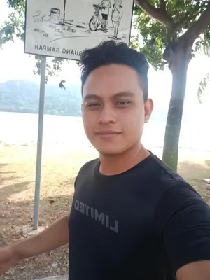 a young man standing in front of a sign at Kedah in Padang Serai