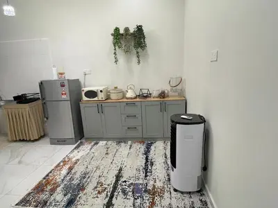 a kitchen with a counter and a refrigerator and a rug at Nadine Homestay in Sungai Petani