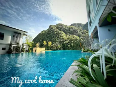 a swimming pool in front of a building with a mountain at Sunway Onsen Suite Theme Park View 2BR in Ipoh