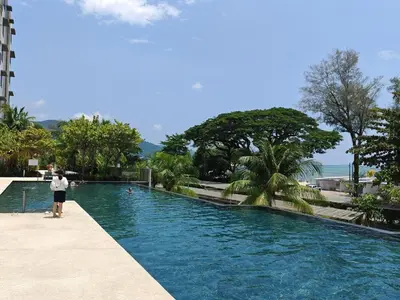 a person standing next to a swimming pool at By the sea Beach Front, Seaview And Pool side in Batu Ferringhi
