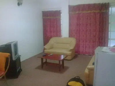 a living room with a yellow chair and a tv at Cameron Highland 3 Bedroom Apartment in Cameron Highlands