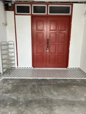 a red door on a white wall with a ladder at Comfortable two-storey terrace house near main road perai in Perai