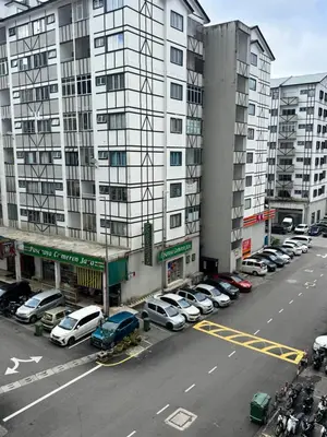 a parking lot with cars parked in front of a tall building at Ayaan Family Retreat with PS4 and Netflix in Tanah Rata