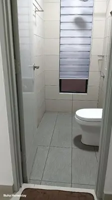 a bathroom with a toilet and a glass shower door at Nuha Homestay La Casa Lunas