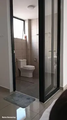 a bathroom with a toilet and a glass door at Nuha Homestay La Casa Lunas