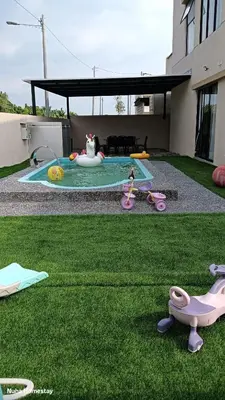 a backyard with a play area with a pool and grass at Nuha Homestay La Casa Lunas