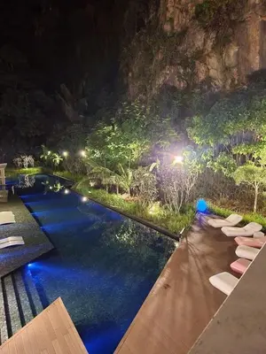 a pool at night with lounge chairs and lights at 3 Bed Rooms Cozy Unit The Cove in Ipoh
