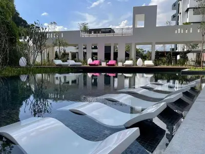 a pool of water with white chairs and a building at 3 Bed Rooms Cozy Unit The Cove in Ipoh